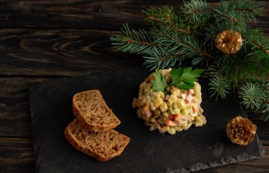 Geleneksel Rus Yeni Yıl Salatası Olivier, Yeni Yıl veya Noel salatası servisi, siyah arka plan, köknar dalları, yeni yıl çevresi. Yüksek kalite fotoğraf