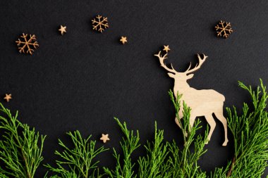 Siyah arka planda noel kompozisyonu, tahta geyik ve köknar, kopyalama uzayı