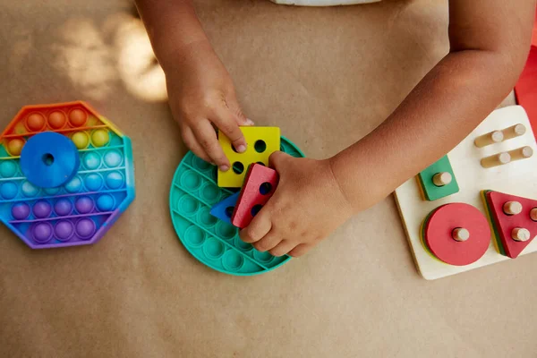 Toddler plays with colorful antistress sensory toy fidget push pop it. Trendy pop it toy for the development of fine motor skills. Rainbow sensory fidget. New trendy silicone toy and wooden eco toys