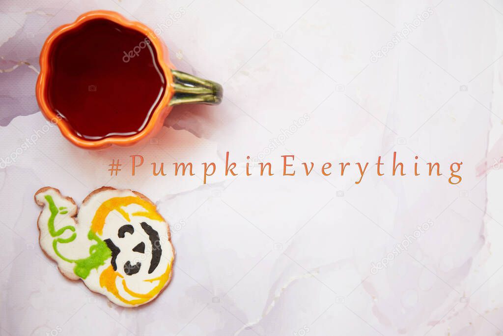 Halloween treats: pumpkin cup and homemade cookie in shape of cute pumpkin. Lettering Pumpkin Everything. Aesthetic autumn mood or trick or treat concept. Autumn cozy home concept. Copy space.