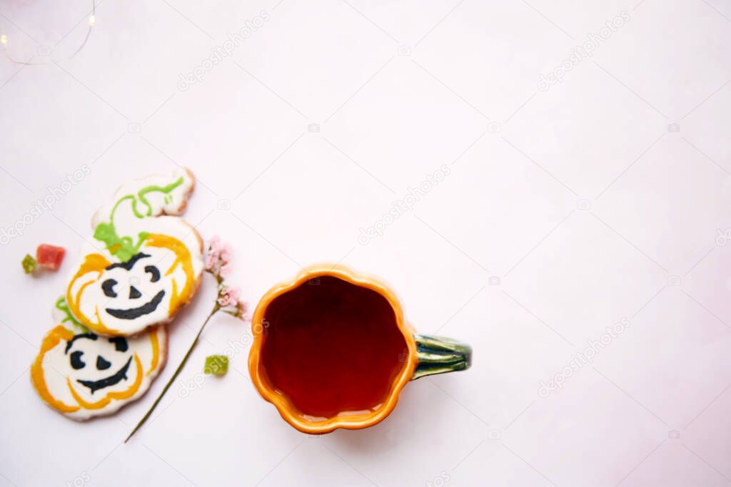 Halloween still life with pumpkin cup with tea and homemade cookies in shape of sweet pumpkins. Bright pink aesthetic autumn holiday or trick or treat concept. Top view. Home cooking and coziness.