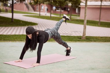 Şapkalı beyaz bir kadın dışarıda egzersiz yapıyor. Açık hava egzersizleri. Sağlıklı yaşam tarzı kavramı. Çömeliyor. Yüksek kalite fotoğraf