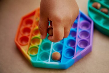 Bebek oyuncak ve fındıkla oynar. Motor becerilerin gelişimi için oyun. Gökkuşağı dokunuşu duyusal dokunuş. Üst Manzara. Yüksek kalite fotoğraf