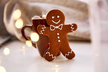 Noel sembolü, ev yapımı zencefilli kurabiye ve bulanık bokeh dekoru. Sıcak içecek ve marşmelovlu Noel süslemeleri. Estetik Noel atmosferi, ev konforu, sıcaklık konsepti