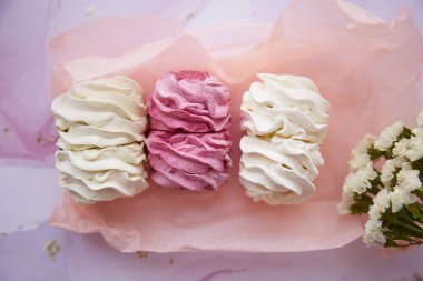 Kuru çiçeklerle süslenmiş yumuşak pembe ve beyaz marşmelov. Kadınsı kart konsepti. Sıcak kış hafta sonları. Ev yapımı tatlılar. Üst Manzara. Yüksek kalite fotoğraf