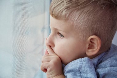 Sevimli çocuk pencereyi işaret ediyor ve yakından bakıyor. Umut, izleme ve bekleme konsepti. Uzayı kopyala Yüksek kalite fotoğraf