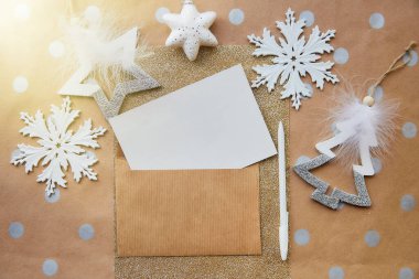 Bej, el işi kırtasiye kartı, zarf maketi, kalem. Temel arka planda moda Noel dekorasyonları. Estetik festival atmosferi. Tebrik kartı gönderme konsepti. Yukarıdan bak. Metin için yer