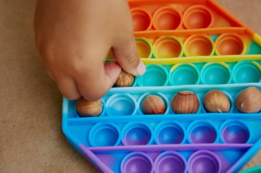 Çocuk pop it toy ve ela ile bir oyun oynuyor. Motor becerilerin gelişimi için oyun. Gökkuşağı dokunuşu duyusal dokunuş. Üst Manzara. Yüksek kalite fotoğraf