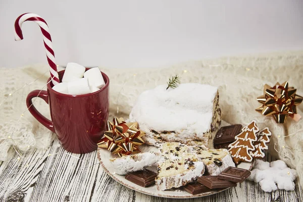Aesthetic red cup with marshmallows and Christmas stollen on ceramic plate - traditional holidays bread, candy cone stick. Festive Christmas background. Christmas tradition food. — Stock Photo, Image