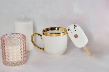 Beyaz fincanlı sıcak öğleden sonra çayı, tatlı marshmallow geyiği, zencefilli kurabiye ve pembe mum. Estetik çay zamanı. Noel ilham konsepti. Günaydın ya da sıcak ev konsepti