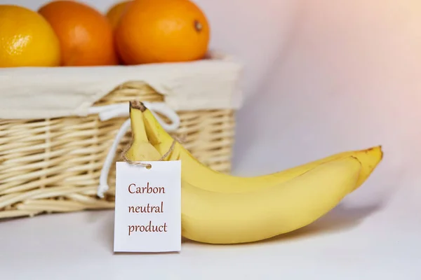 Carbon neutral product label on bananas. Carbon labeling. Basket of oranges on background. Net zero carbon, emissions free. Organic farm products from local market.