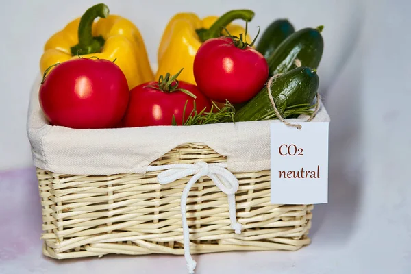 Wicker basket with carbon neutral product label on fresh vegetables. Carbon labeling. Net zero carbon, emissions free. Organic farm products from local market. Fresh tomatoes, cucumbers, bell pepper