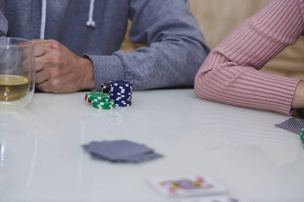 Kadın ve erkek poker oyunu oynuyor. Fişler, kartlar, masaya yansıyan bir bardak viski. Yaşam tarzı fotoğrafçılığı. Poker kulübü.