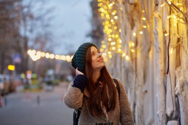 Sokakta yürüyen rüya gibi beyaz bir kadın. Şehir ışıkları. Kış kıyafetleri. Akşamları şenlikli bir şehir. Boşluğu kopyala