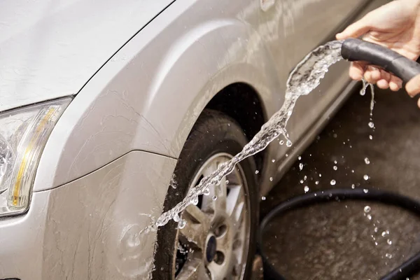 Lavando el coche con agua de debajo de las mangueras. Rutinas caseras. El cuidado de su vehículo — Foto de Stock