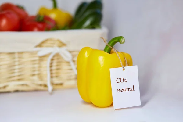 Carbon neutral product label on bell pepper. Carbon labeling. Basket of vegetables on background. Net zero carbon, emissions free. Organic farm products from local market.