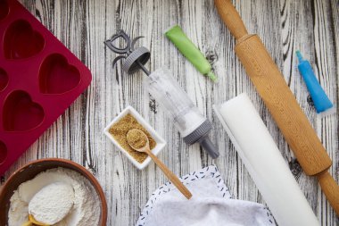 Mutfak gereçleri ile pişirme hazırlığı: kalp şeklinde silikon kalıp, merdane, şekerleme şırıngası, cam, un, pembe arka planda şeker. Sevgililer Günü konsepti.