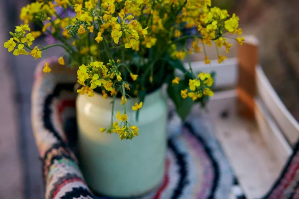Természetes évjárat színes kézzel készített szőnyeg és tavaszi virágok öntözőkannában. Vidéki élet, kunyhó mag, kreatív rusztikus patchwork koncepció. — Stock Fotó