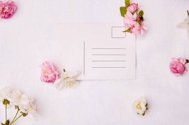 Bahar pembesi ve beyaz çiçekler ve üzerinde adres olan kartpostallar. Davetiye, romantik, düğün, doğum günü, anneler günü kartı konsepti. Uzayı kopyala Üst görünüm.