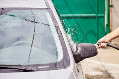 Arabayı hortumların altından suyla yıkamak. Ev rutinleri. Araç bakımı.