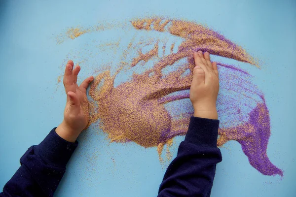 Bebekler renkli kumlarla oynarlar. Çocukların motor becerileri gelişiyor. Yaratıcı çocuk mesleği. Yukarıdan görüntüle
