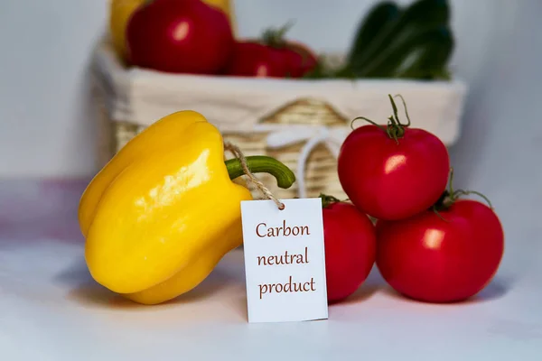 Carbon neutral product label on tomatoes and yellow bell pepper. Carbon labeling. Net zero carbon, emissions free. Organic farm products from local market. Basket of vegetables on background