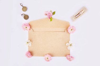 Pembe çiçekleri, aksesuarları, saç tokası, küpeleri olan minimalist kadınsı bir bahar zarfı. 8 Mart kavramı