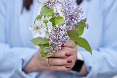 Kadınların elindeki estetik bahar çiçekleri kapanıyor. Leylak ve kayısı çiçek açıyor. Bahar arkaplanı. 