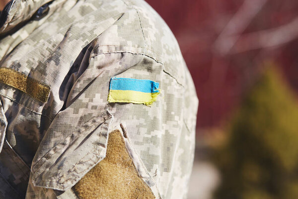 Ukrainian flag on uniform of soldier close up. Stop russian aggression. Stop war in Ukraine. Stay with Ukraine. Breaking news. Pray for Ukraine. Copy space.