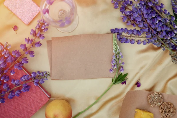 Kağıt maketi. Yaz kadınsı daveti, doğum günü kartı, anneler günü konsepti. Lupins mor çiçekler, elma ve kurabiye süslemeleri. Canlı bir arka plan. Doğal, sağlıklı doğaya yakınlık..
