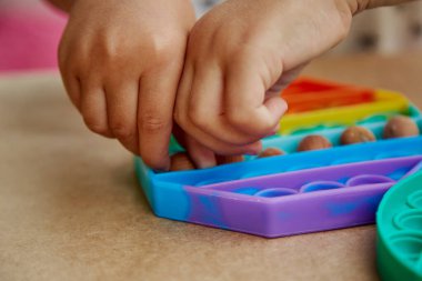 Bebek eller, pop it toy ve ela ile bir oyun oynuyor. Motor becerilerin gelişimi için oyun. Gökkuşağı dokunuşu duyusal dokunuş. Üst Manzara. Yüksek kalite fotoğraf