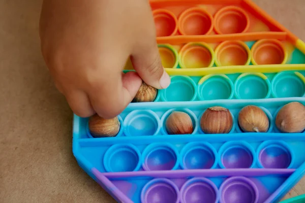 Çocuk pop it toy ve ela ile bir oyun oynuyor. Motor becerilerin gelişimi için oyun. Gökkuşağı dokunuşu duyusal dokunuş. Üst Manzara. Yüksek kalite fotoğraf