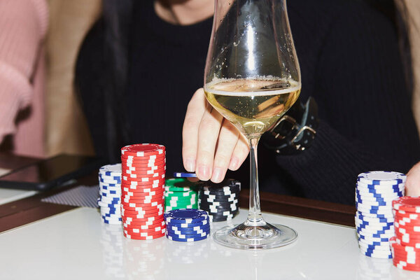 Woman hand making a move with dice in poker game. Cards, dices and glasess of champagne. Candid moment. Poker background lifestyle photography. Enjoying the moment, digital detox with friends