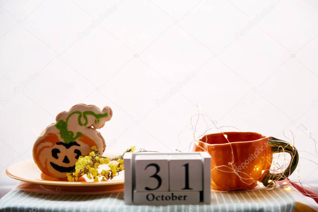 Happy Halloween still life with pumpkin cup and homemade cookies in shape of cute pumpkins and date of Halloween Day. Atmospheric aesthetic autumn holiday concept. Rural life. High quality photo
