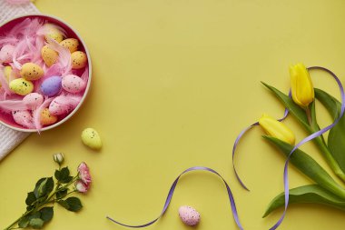 Paskalya 'nın parlak geçmişi. Renkli yumurtalı pembe kase, pembe tüyler, bahar çiçekleri. Mutlu Paskalyalar. Kopya alanı olan kartpostal.