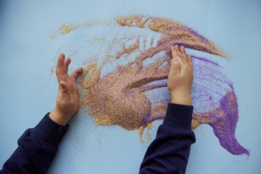 Bebekler renkli kumlarla oynarlar. Çocukların motor becerileri gelişiyor. Yaratıcı çocuk mesleği. Yukarıdan görüntüle