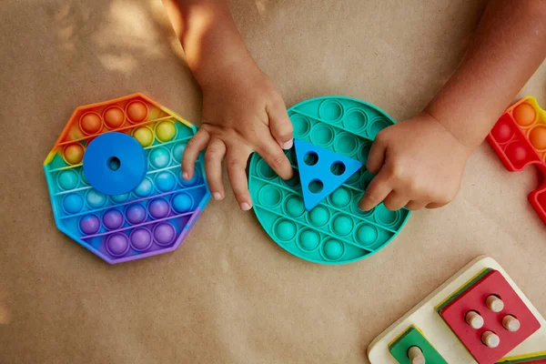 Baby hands plays with colorful antistress sensory toy fidget push pop it . Trendy pop it toy for the development of fine motor skills. Rainbow sensory fidget. New trendy silicone toy and wooden eco toys. High quality photo