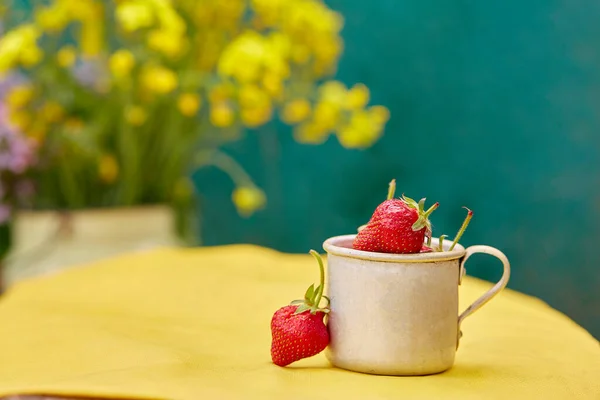 Strawberries in a metal aluminum travel mug. Green and yellow spring background. Cottagecore aesthetics concept, trendy shadows background. Copy space. High quality photo
