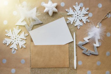 Bej, el işi kırtasiye kartı, zarf maketi, kalem. Temel arka planda moda Noel dekorasyonları. Estetik festival atmosferi. Tebrik kartı gönderme konsepti. Yukarıdan bak. Metin için yer