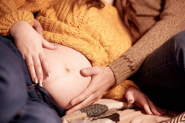 Gentle touching on the tummy of pregnant woman. Tenderness pregnant couple close up. Big tummy. Young family at home. High quality photo