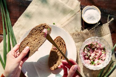 Ekmeğe sağlıklı turp sürüyorum. Sağlıklı atıştırmalık. Ekmek hamuru üzerine taze soğan sürülmüş organik turp. Dışarıdaki doğal gölgelerin altında tuz. Kırsal, organik yiyecekler..