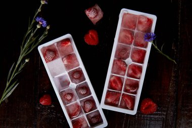 Biçimlerde çilek buzu. Yaz buzunu parti kokteylleri, dondurma ve tatlılar için hazırlıyorum. Tazelik. Yaban çiçekleri süslemeleri. Boşluğu kopyala.