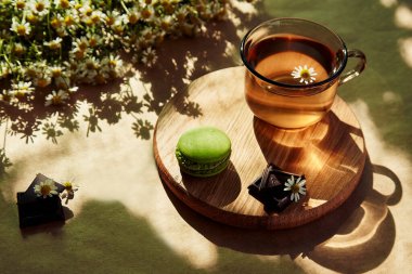 Dışarıda estetik çay saati, terasta bitkisel çay ve kurabiye tatlısı, modaya uygun sert gölgeler altında. Güzel tatlılar, doğal papatya çayı - sürdürülebilir çevre dostu yaşam tarzı.