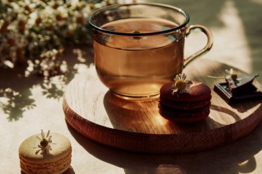 Çay saatinin estetik brançı, bitkisel çay ve kurabiyeli tatlı dışarıda terasta, modaya uygun sert gölgeler altında. Tatlı tatlılar, doğal bitki çayı. Doğal sürdürülebilir çevre dostu yaşam tarzı..