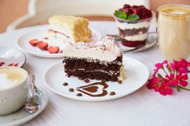 Doğal vejetaryen, katmanlı tatlılar, taze meyve ve meyveli pastalar ve bir bardak latte. Kutlama, terasta çeşitli tatlılar..