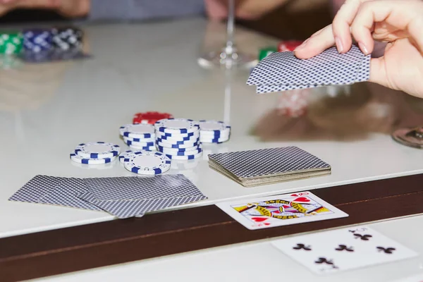 Laying out cards on the table in poker game. Glass of champagne. Gambling concept. Candid moment. Poker background photography. Selective focus.