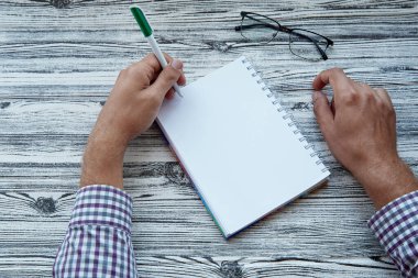 Man writing in notepad mock up, using his left hand. Conceptual photo of lefthanded day. Copy space