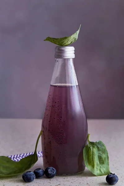 Non-alcoholic healthy organic bottle of drink with blueberries, seeds, basil extract, leaves. Soft refreshing Asian drink.
