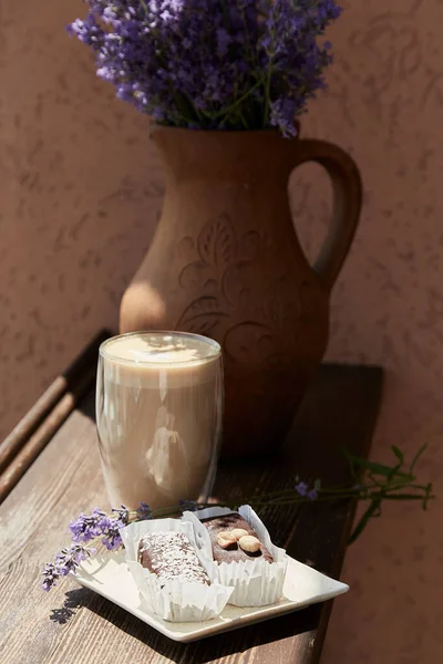 Chocolate dessert with glass of latte and lavender flowers outside in the cafe terrace. Summer breakfast, coffee time. Hard shadows.