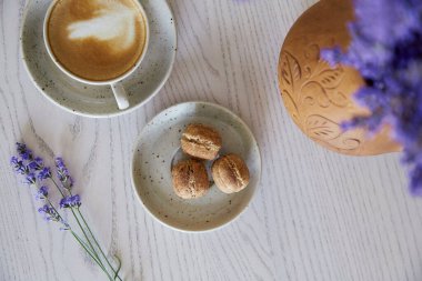  Vegan natural nuts sweets with no sugar. Cup of cappuccino on wooden table in the cafe. Natural sweets. Coffee break. Lavender decorations
